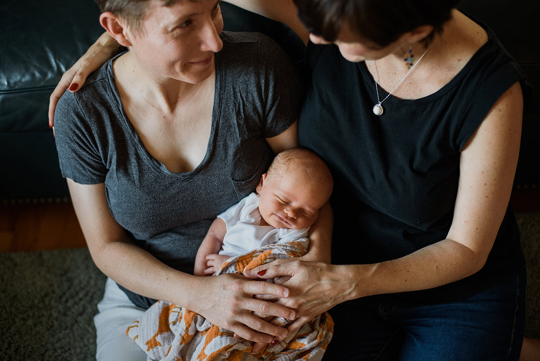 Smiling baby with his mothers during an at-home newborn session in Roanoke, Virginia