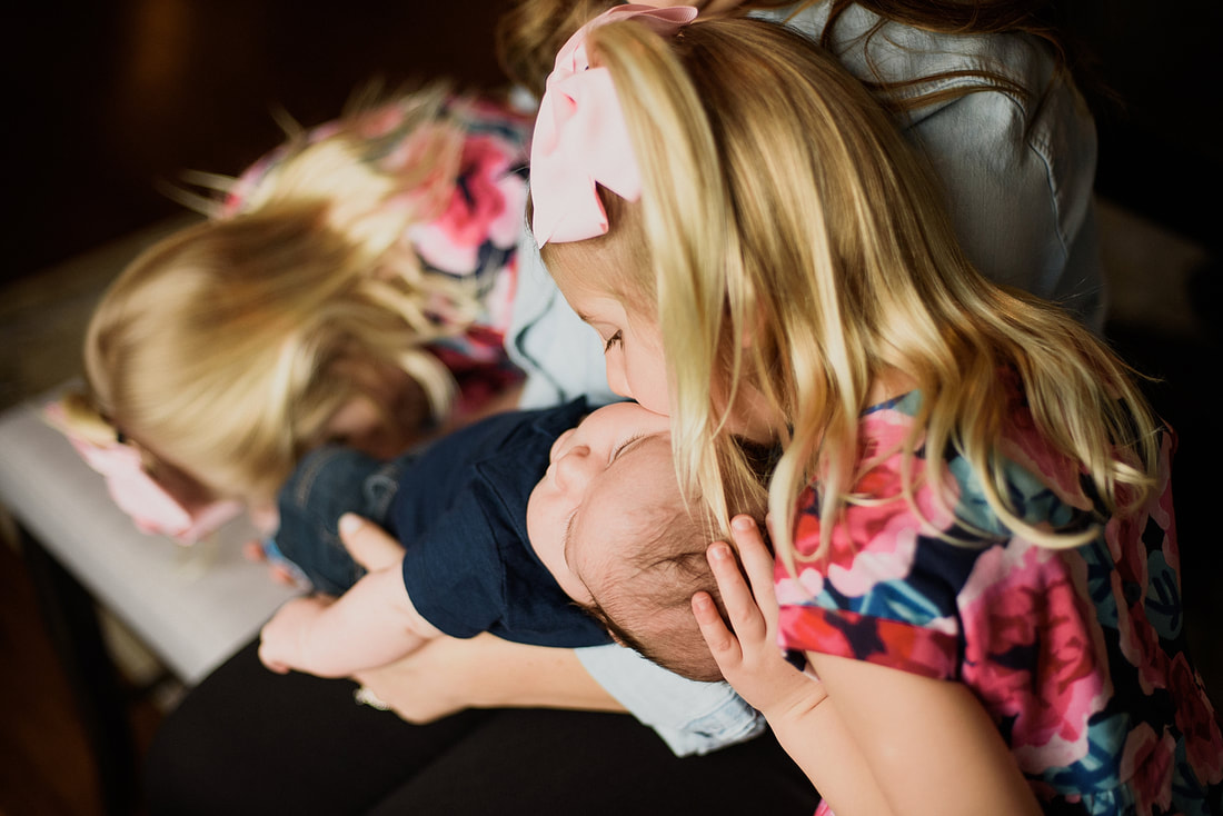 Big sister kissing her new baby brother during a lifestyle newborn photography session in Roanoke, Virginia